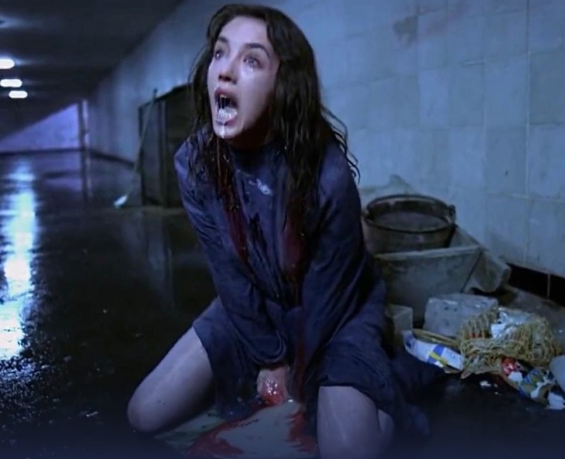 a woman sitting on the ground with blood dripping from her mouth